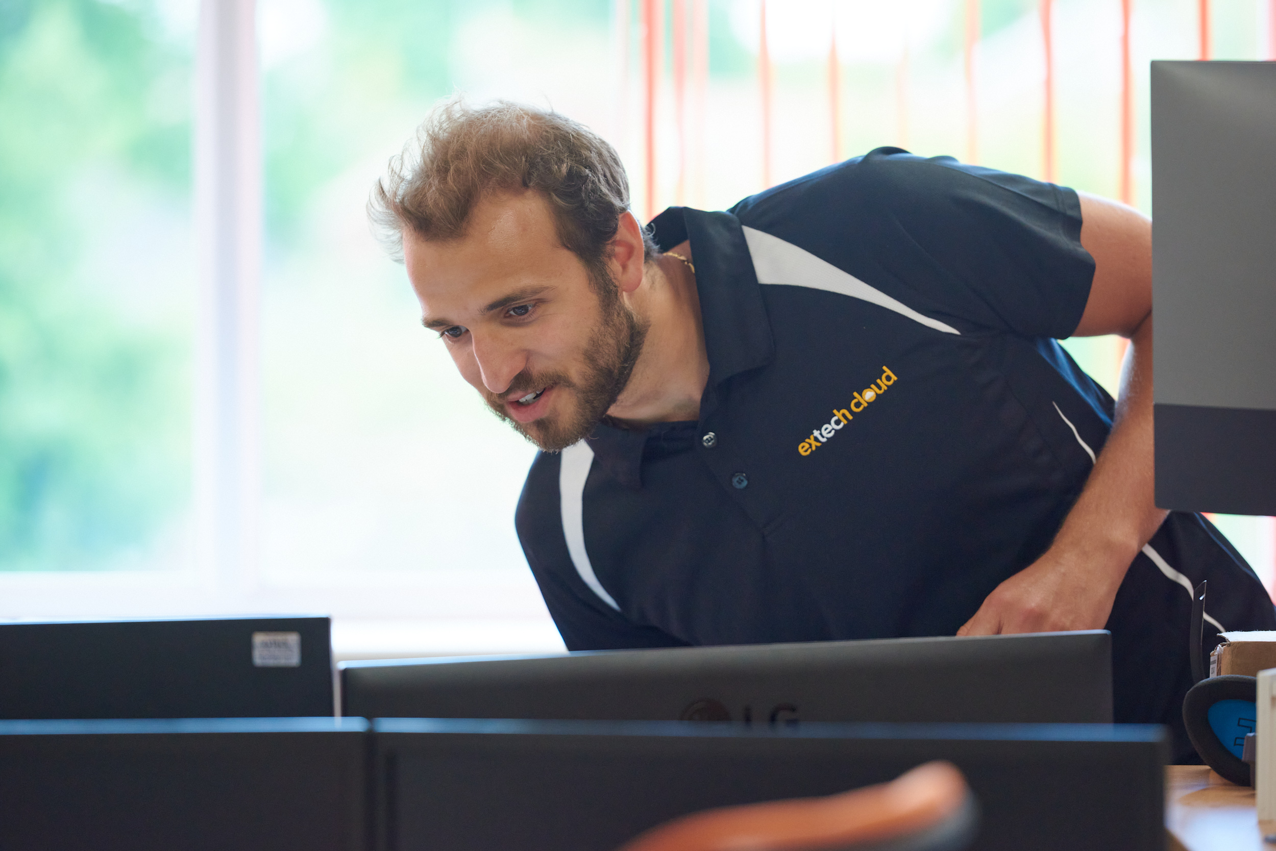 Extech Cloud team member leaning over computer hardware